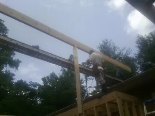 Carpenter setting a ridge beam over a new addition frame — Ice Dam Removal by Roofing Brothers in Taylors