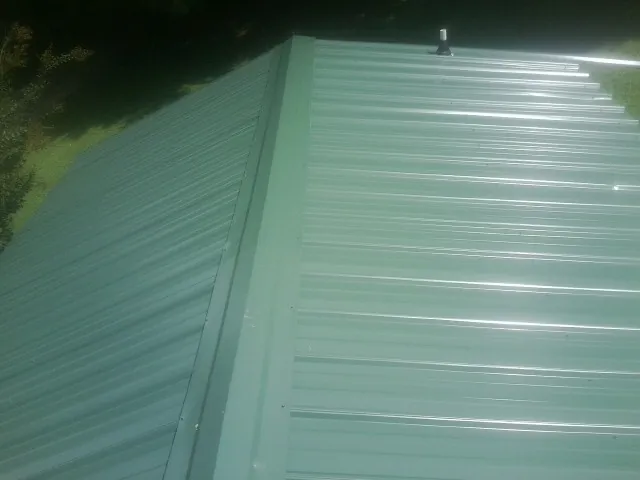 New green metal panels meeting at the ridge of a roof — Flat Roof Repair work by our crew in Taylors
