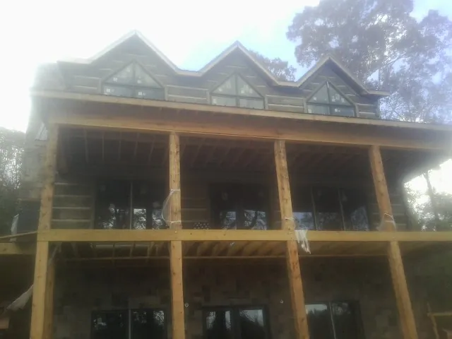 Dormers and porch framing on a large log home under construction — Roof Coating work by our crew in Taylors