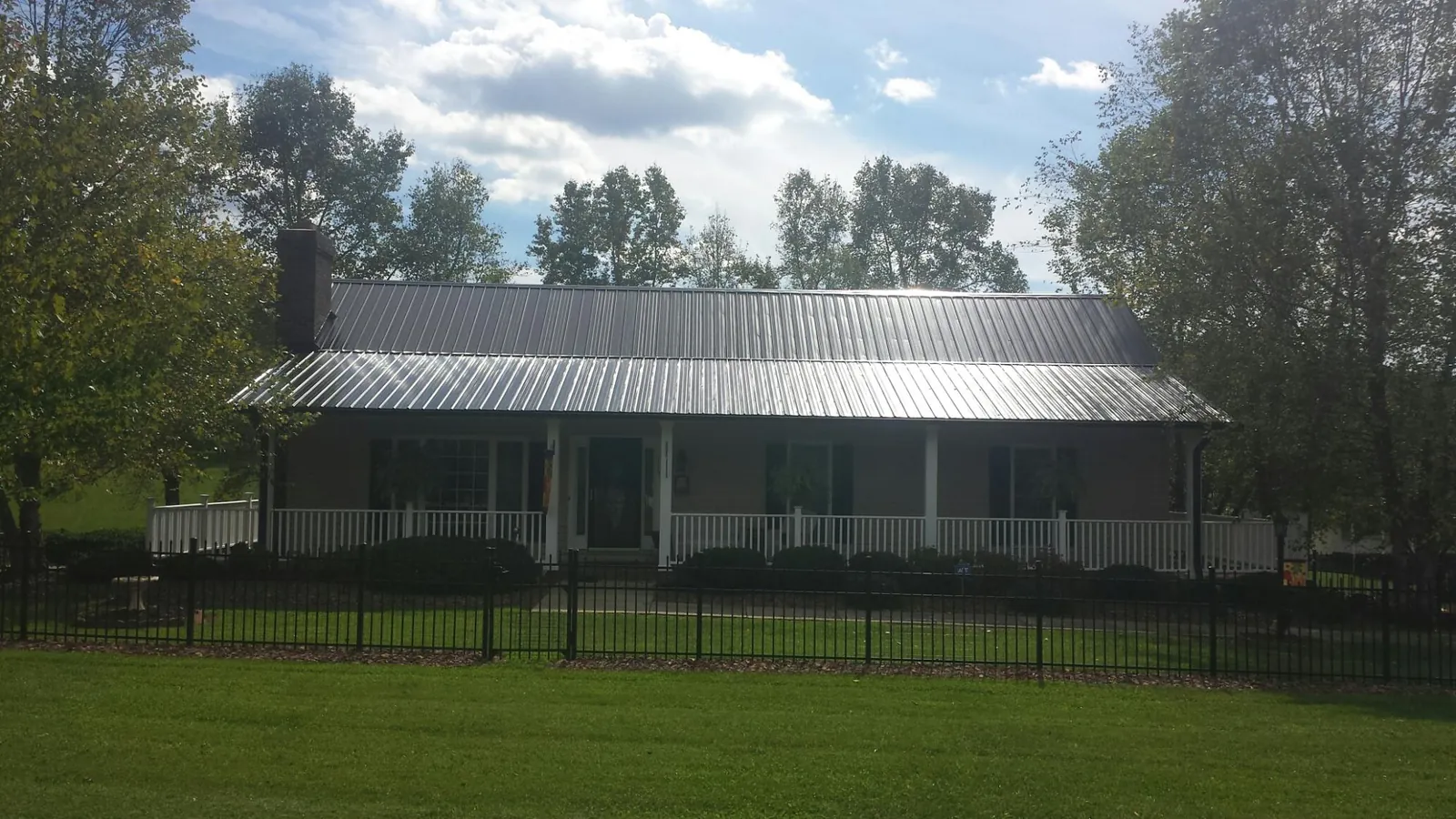 Gray metal roof on a brick ranch with a full width front porch — Gutter Guard Installation work by our crew in Taylors