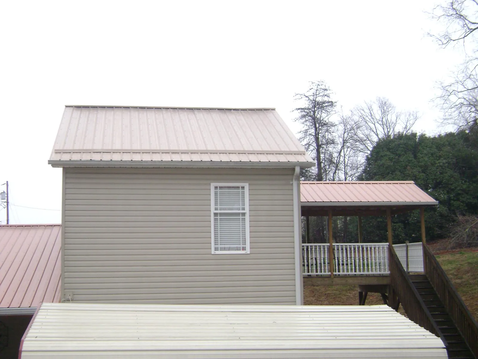 Tan metal roofs on a two story addition and attached porch, from a Roof Replacement job in Taylors
