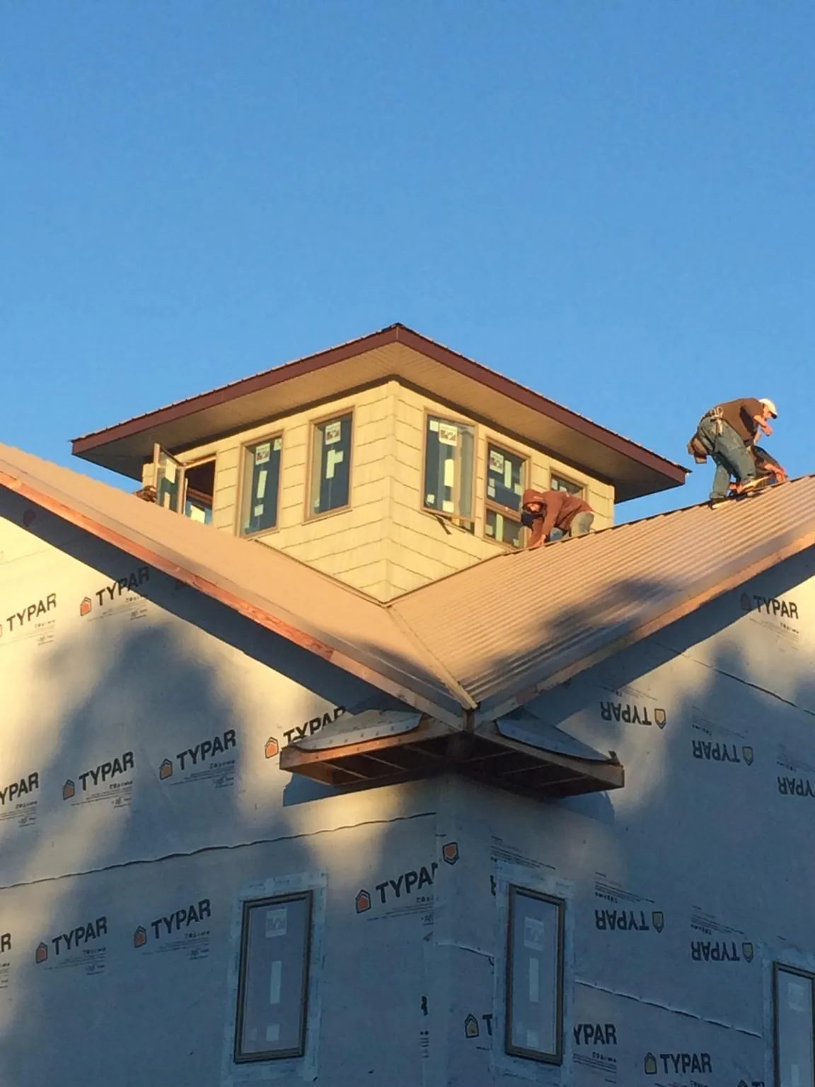 Roofers working around a rooftop cupola on a new metal roof at sunset — Roof Waterproofing in Taylors by Roofing Brothers